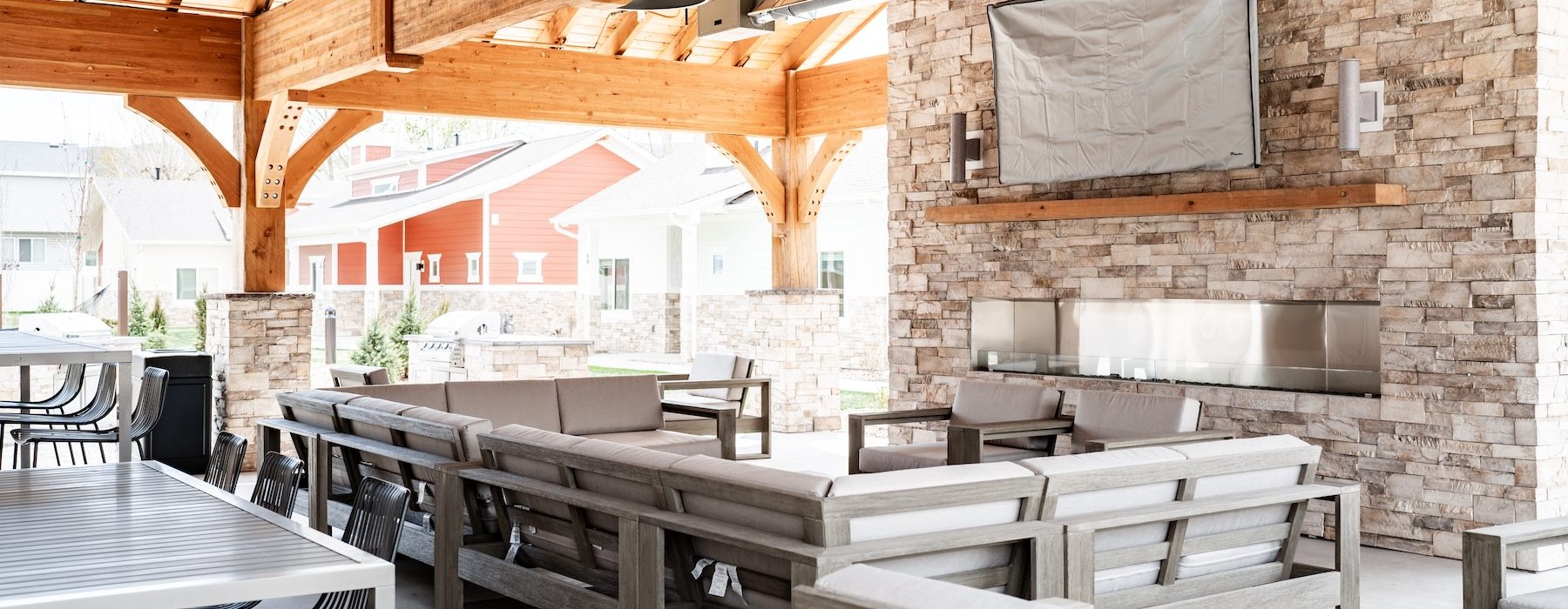 an outdoor lounge with a tv, couch, tables and chairs